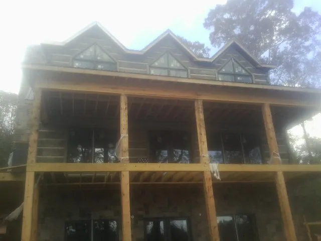 Dormers and porch framing on a large log home under construction — Roof Coating work by our crew in Stratton